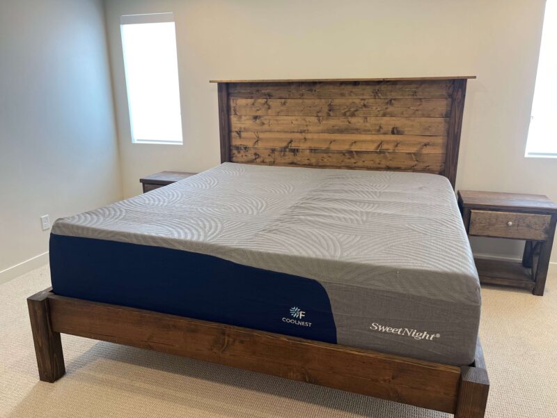 SweetNight CoolNest mattress on a dark wood bed frame with a paneled headboard, featuring a gray textured top and navy blue side panel with white logo text.