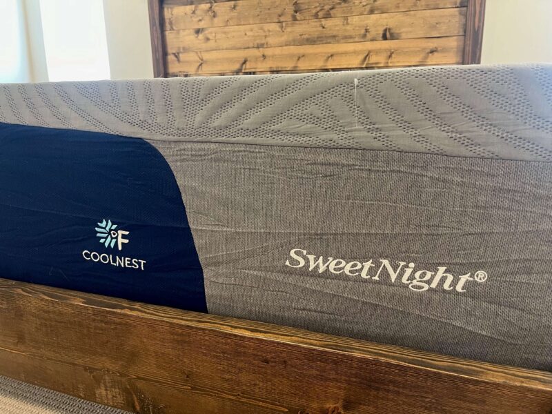 Close-up of the SweetNight CoolNest mattress corner showing the navy blue side panel with the CoolNest and SweetNight logos and the gray textured top cover.