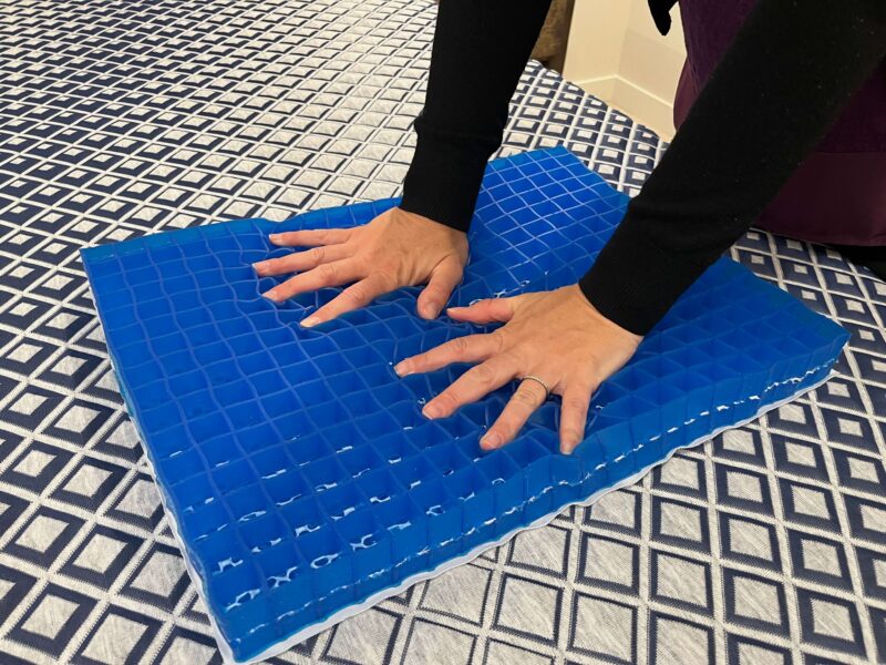 Two hands pressing into a blue grid-cut foam layer from a FORM Prime mattress.