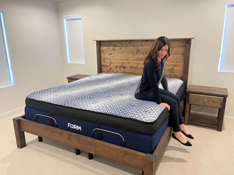 Woman sitting on the edge of the FORM Prime X mattress, demonstrating edge support.